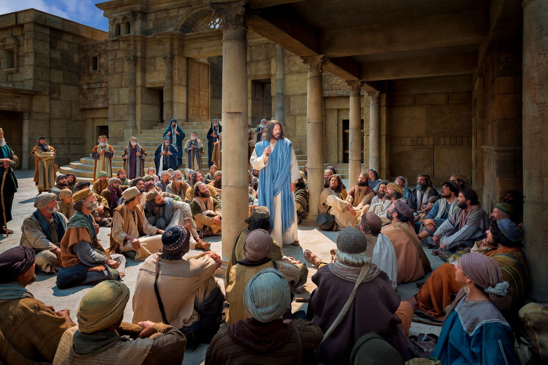 Jesucristo, con un manto azul, enseñando a una multitud sentada en el suelo de un patio de piedra.