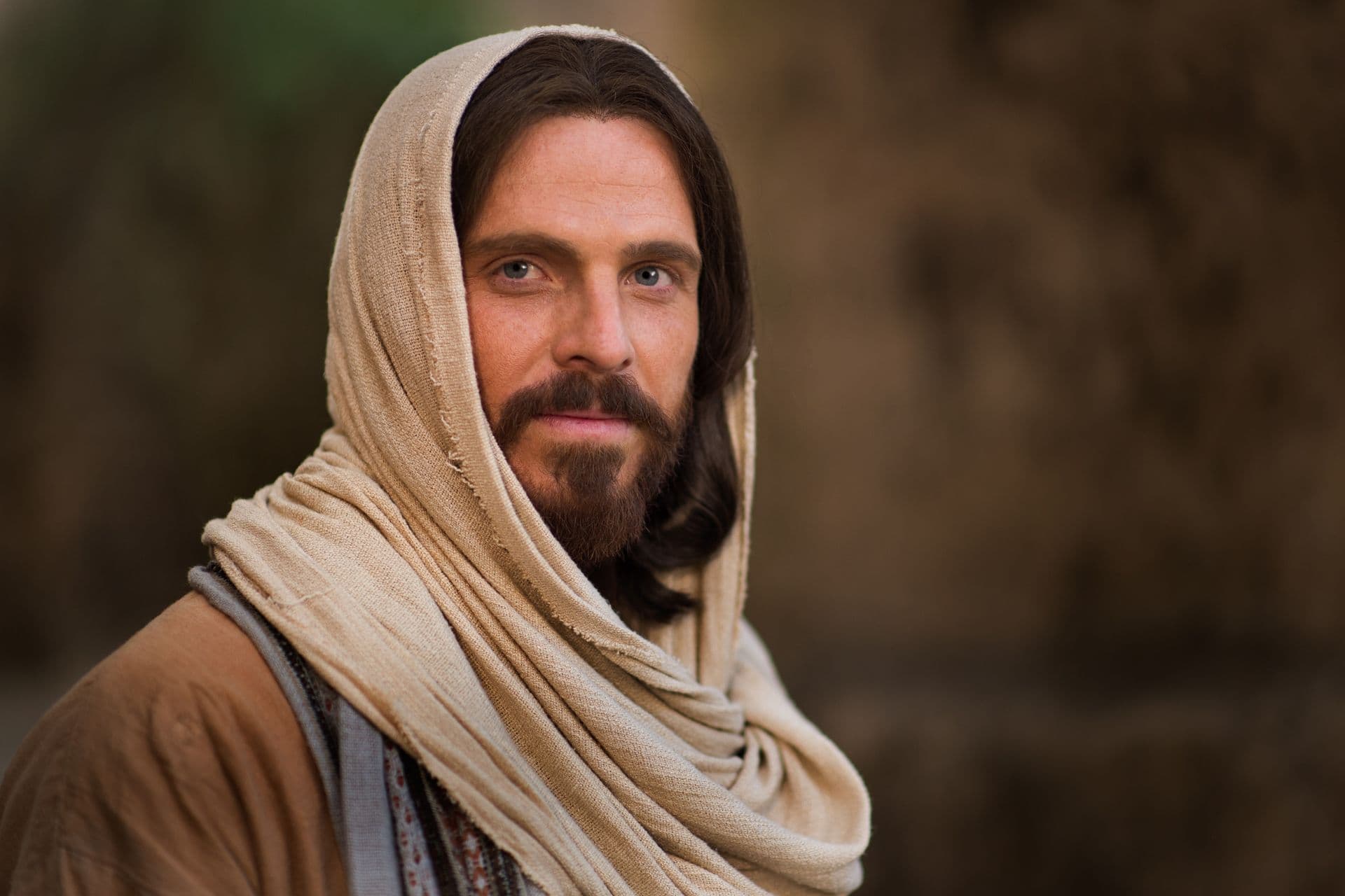 Un retrato de Jesucristo con un manto y una túnica color crema, mirando hacia el espectador.